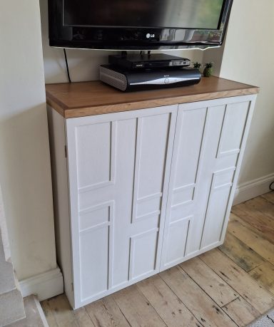 Media storage with veneered top and decorative doors.